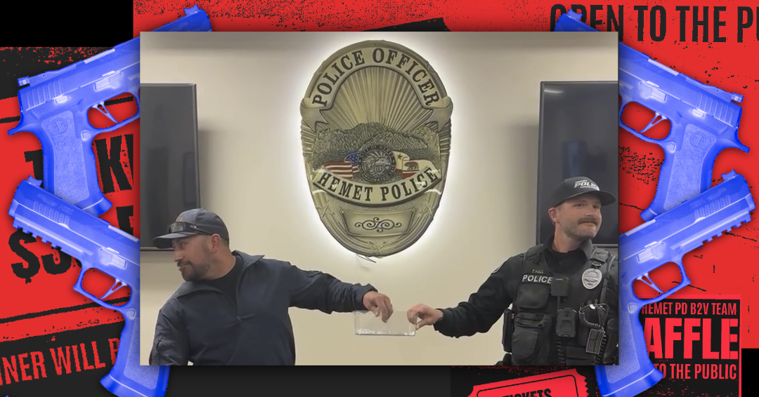 Two police officers stand next to each other pulling a name out of a clear box. Above them is a Hemet Police Department badge. Behind them are four guns and fliers for a raffle.