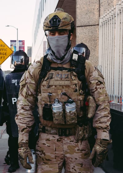 A federal law enforcement officer in military gear stands outside the Metropolitan Detention Center at an anti-ICE rally in downtown LA
